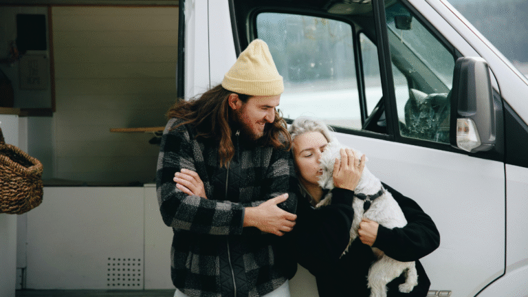 Couple cuddles their dog outside their camper van conversion
