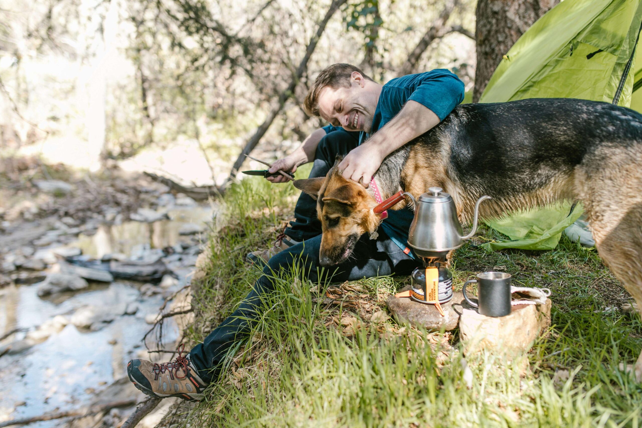 A man smiles whilst stroking his dog at their campsite in Snowdonia National Park