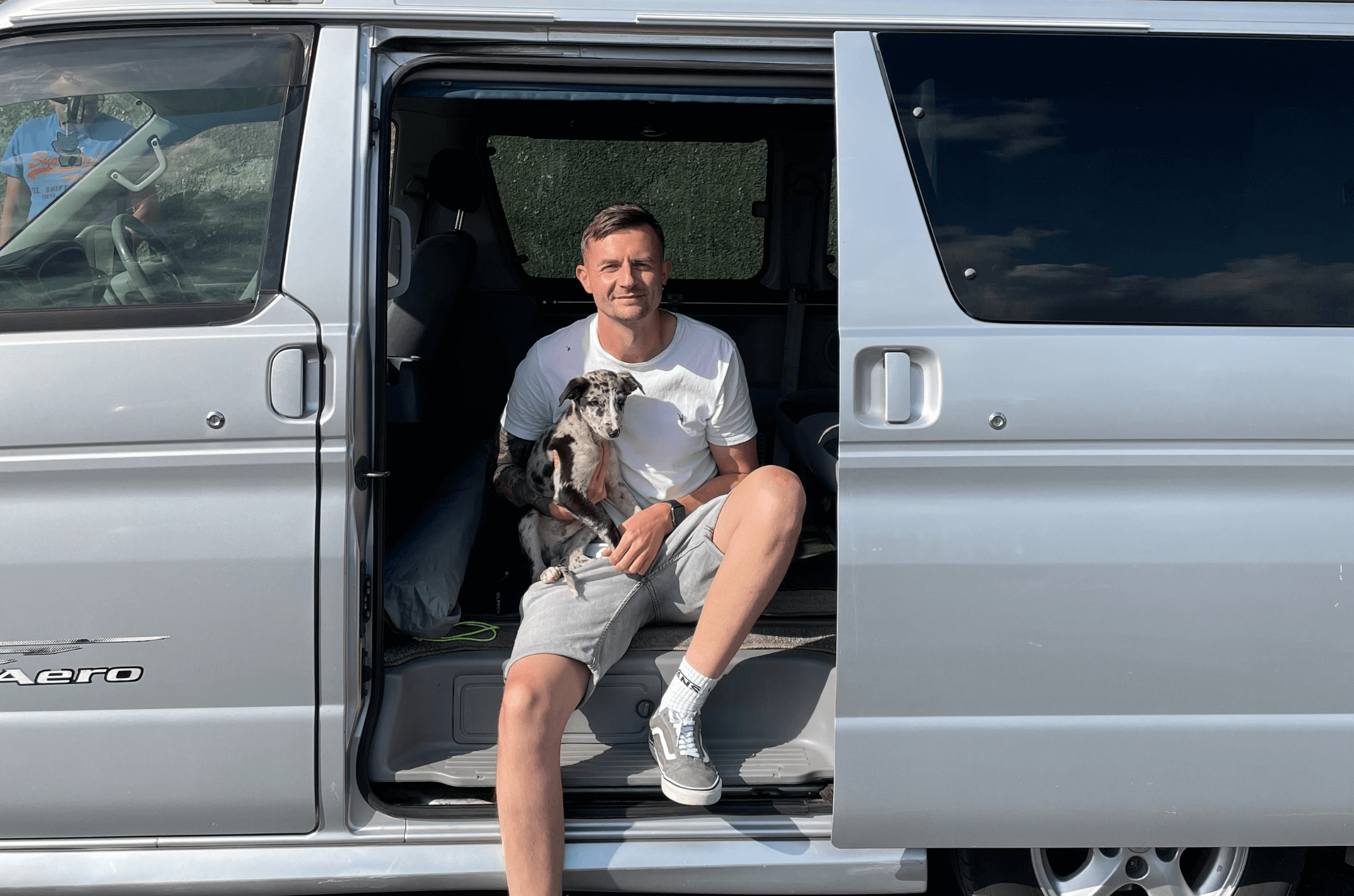 Sam and (puppy) Bowie are sat in the back of his van 