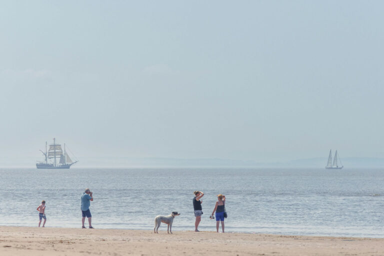A family enjoy a dog friendly day out on Crosby Beach in Merseyside